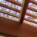 Covered wooden deck overlooking a grassy yard and trees, with lattice roof and railing.