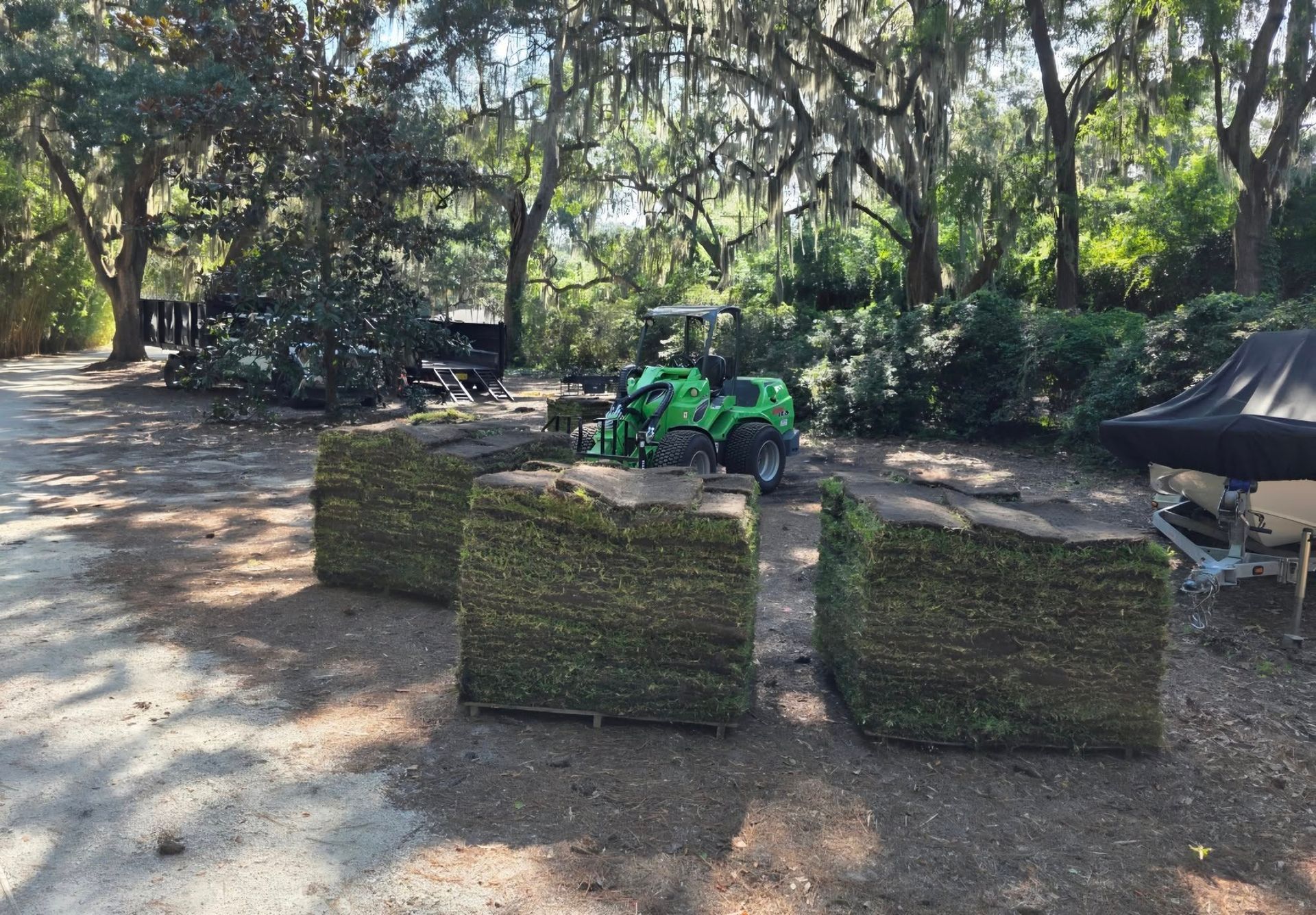 Outdoor paintball field with green barriers, a green ATV, and trees in the background