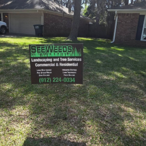 Lawn sign for tree service in front yard, with a house and parked truck in the background.