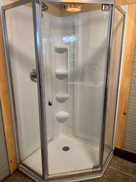A shower stall with a glass door and shelves in a bathroom after boone nc cleaning services