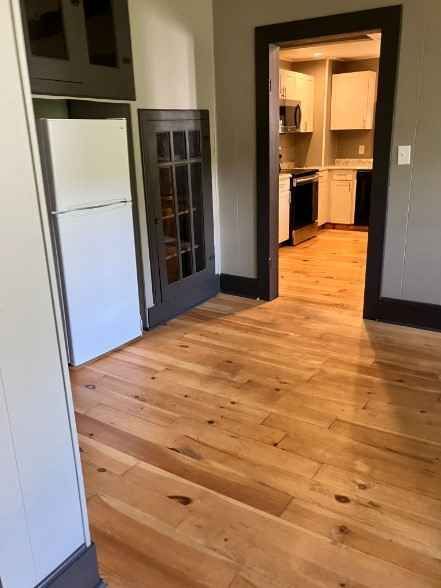 An empty room with hardwood floors and a refrigerator after house cleaning services boone nc