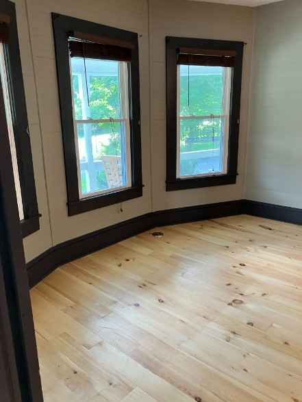 An empty room with wooden floors and two windows after cleaning services boone nc.