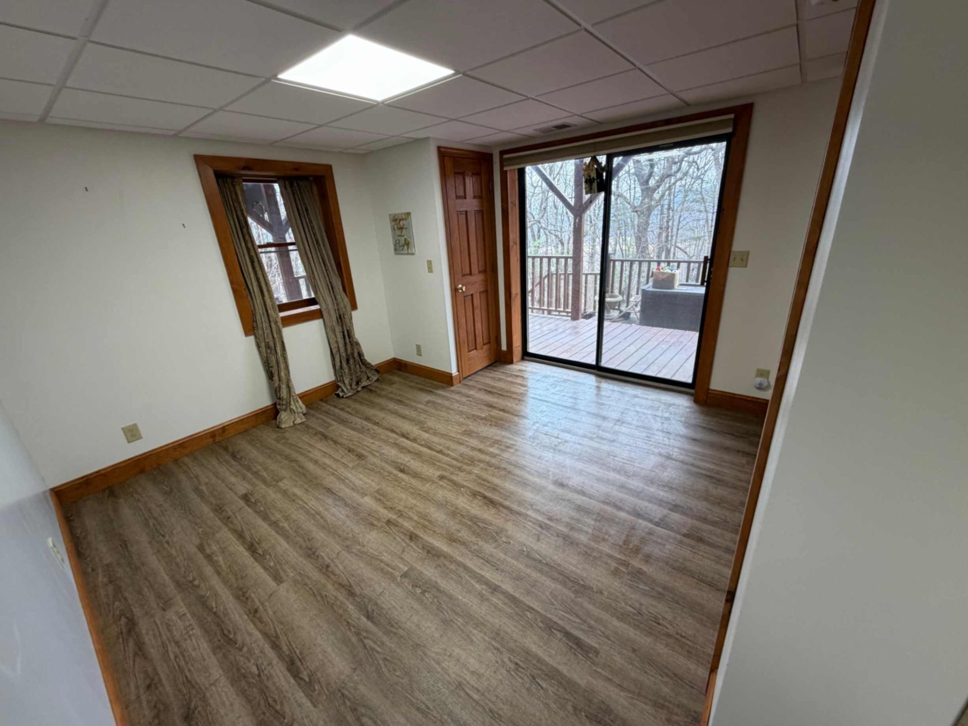 Empty room with wood flooring, white walls, and a sliding glass door to a balcony.