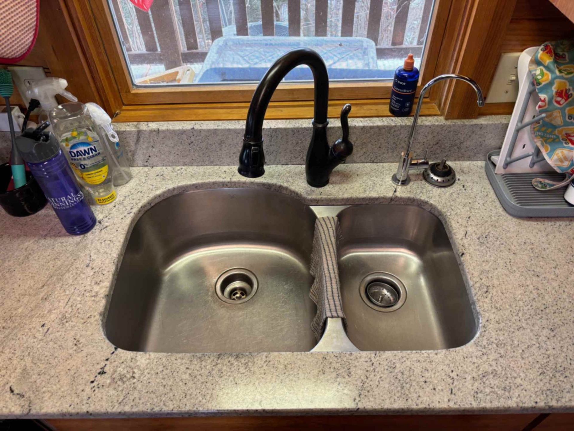 Kitchen sink with two basins, black faucet, and window over the countertop