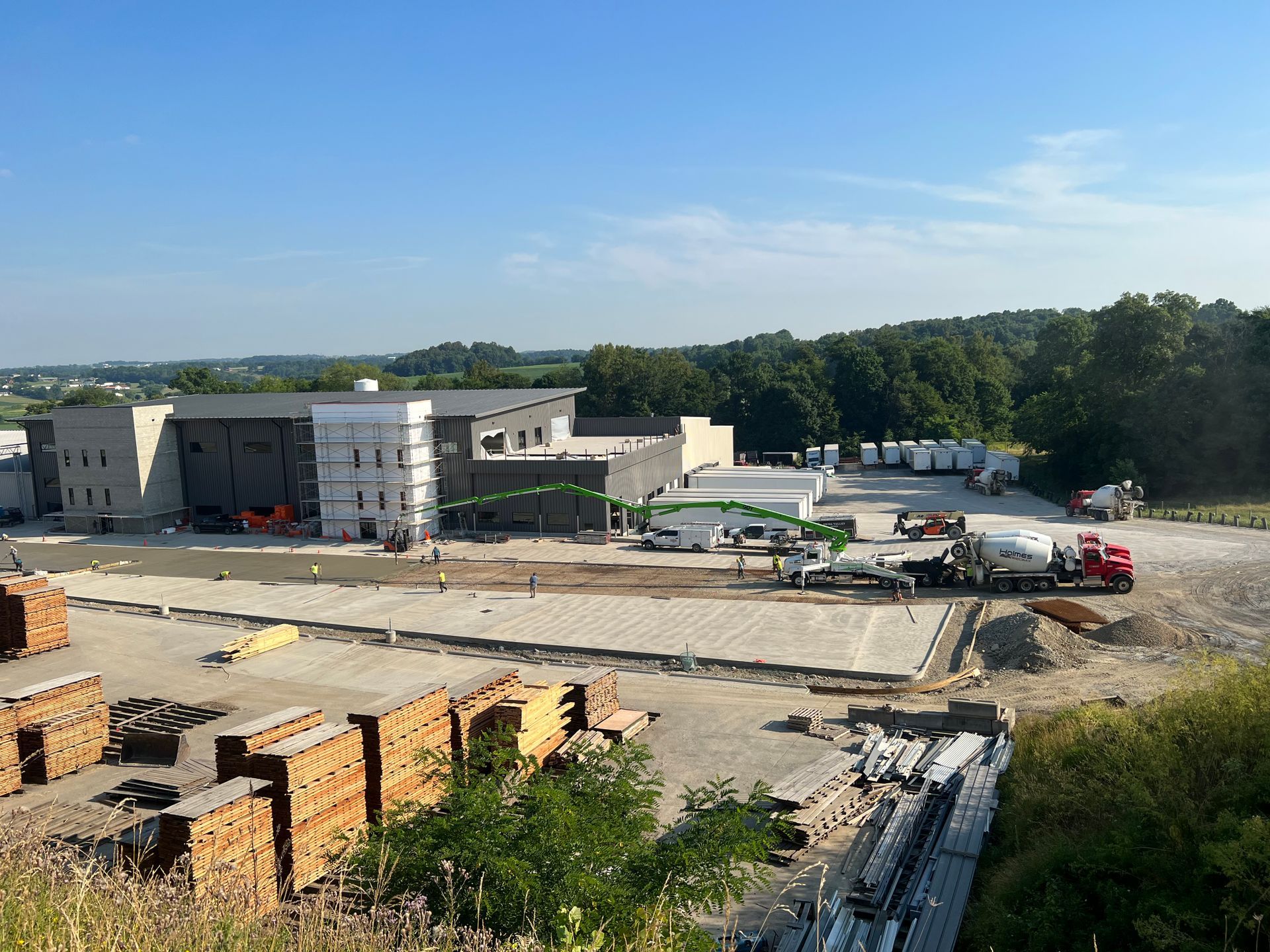 Construction site; concrete being poured; buildings in background; lumber and equipment visible.