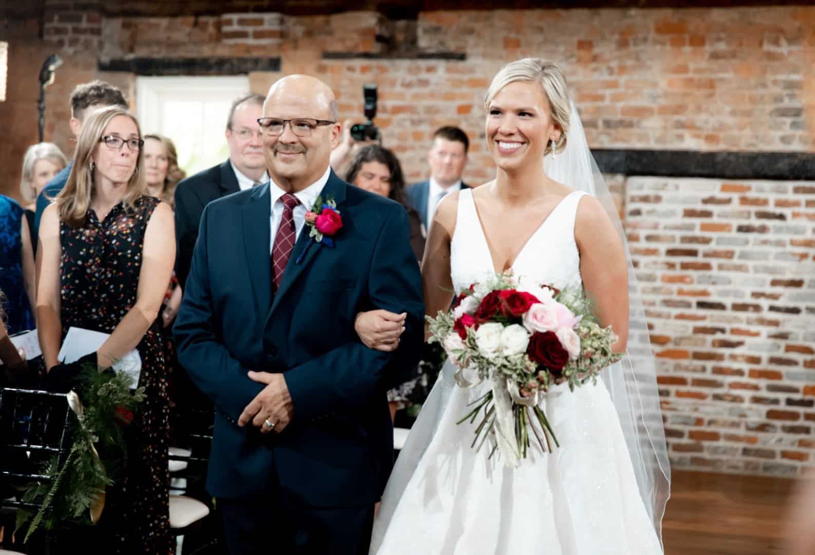 A bride is walking down the aisle with her father at her wedding.