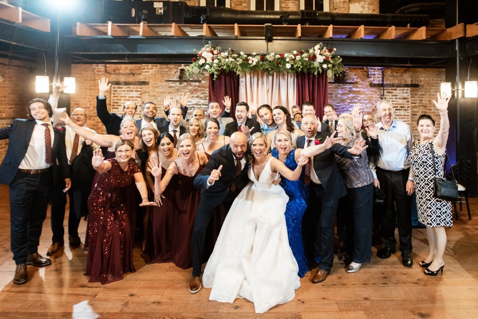A large group of people are posing for a picture at a wedding reception.