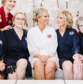 A group of women are sitting on a couch and one of them has a monogram on her robe