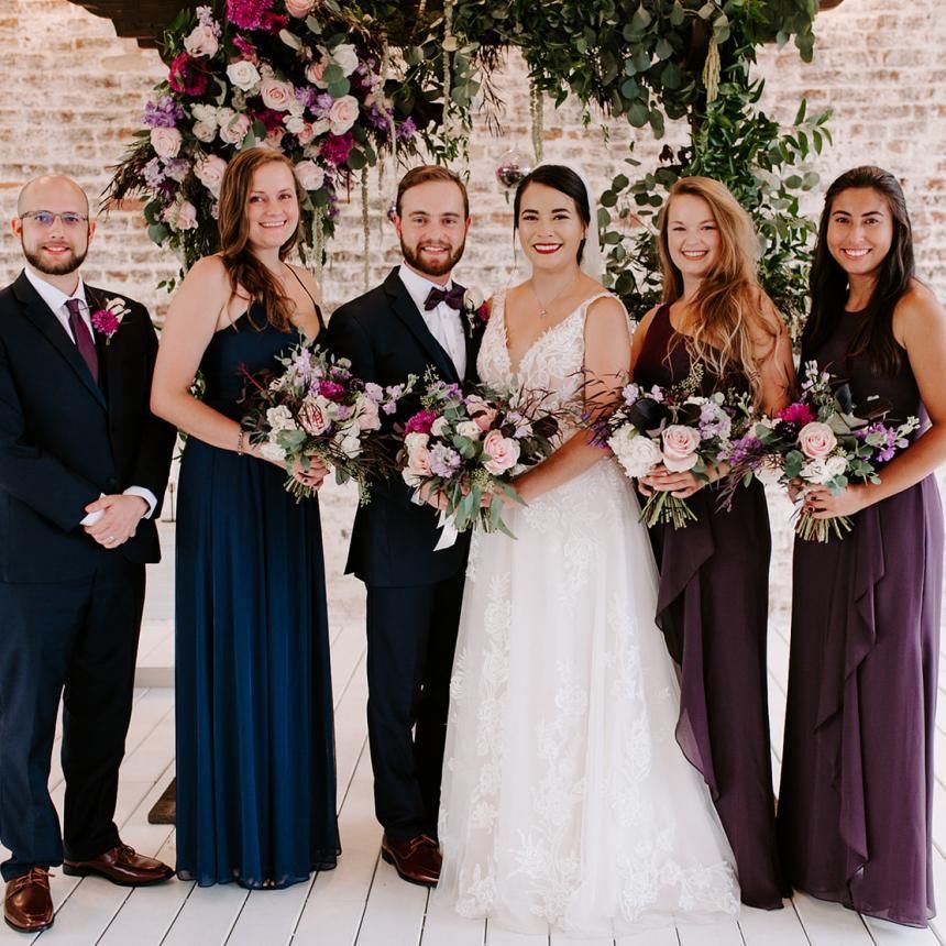 The bride and groom are posing for a picture with their wedding party.