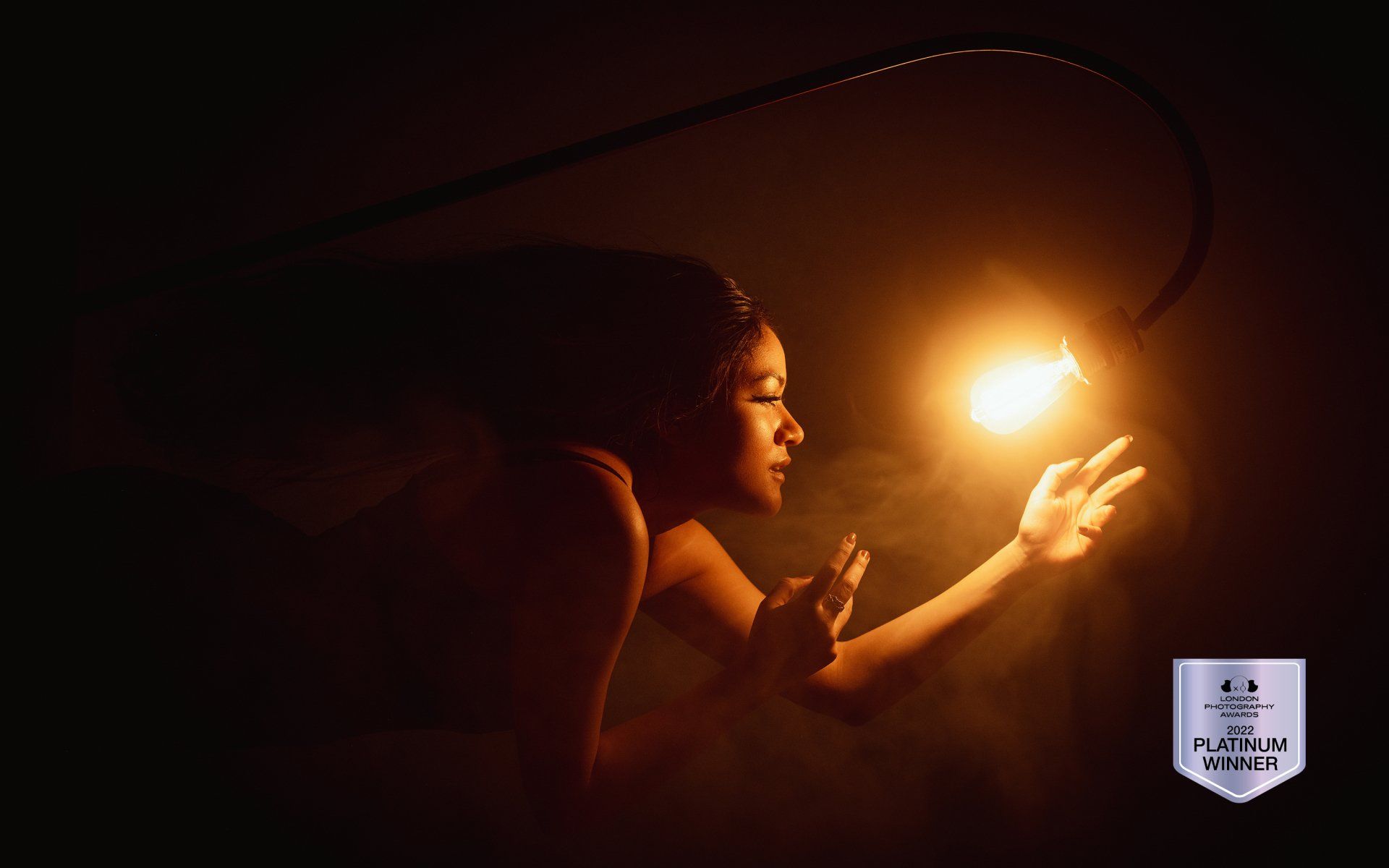 portrait of a woman reaching out for a lightbulb
