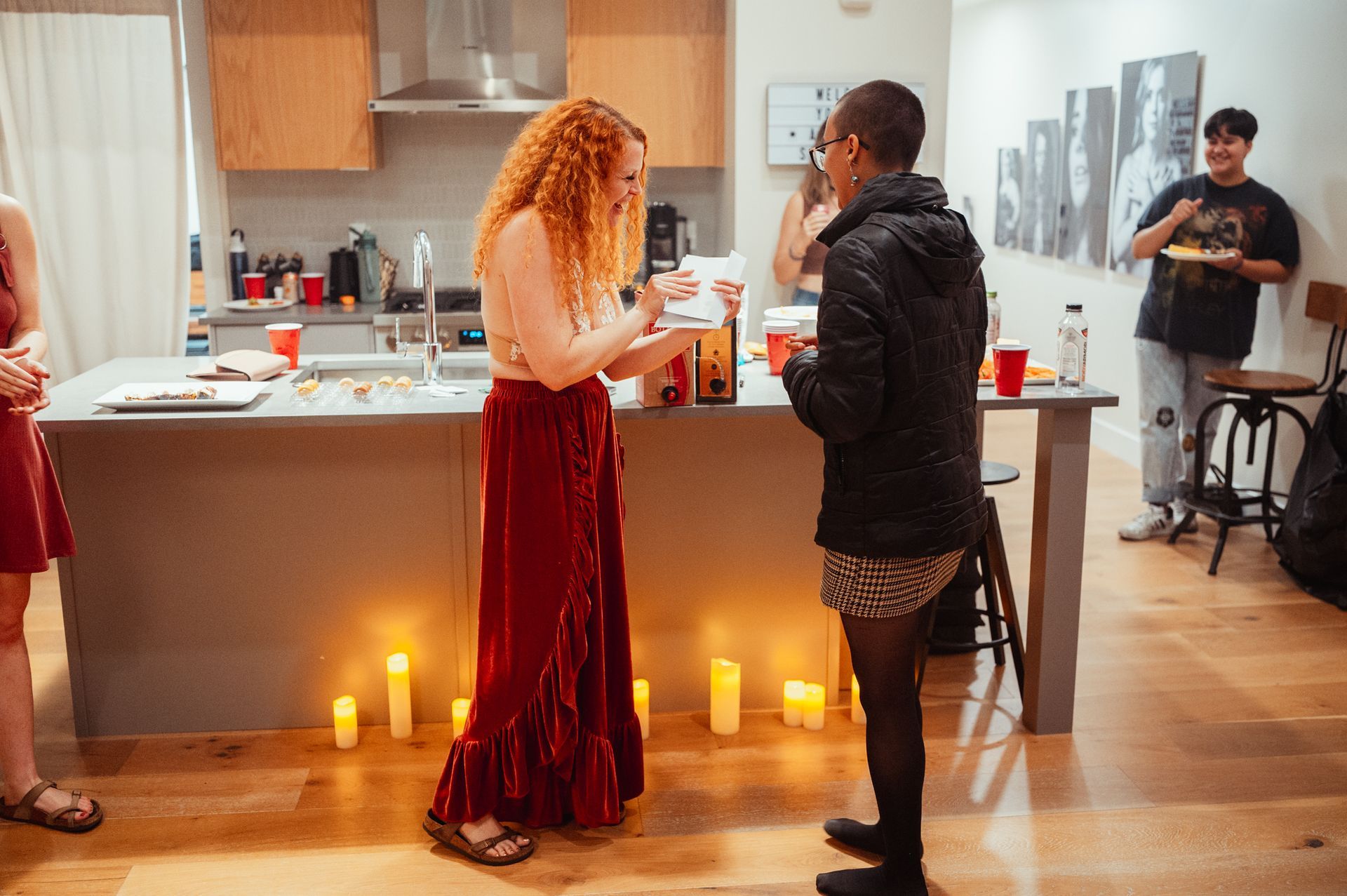 Two women stand together at a kitchen counter adorned with candles, creating a warm and inviting atmosphere.