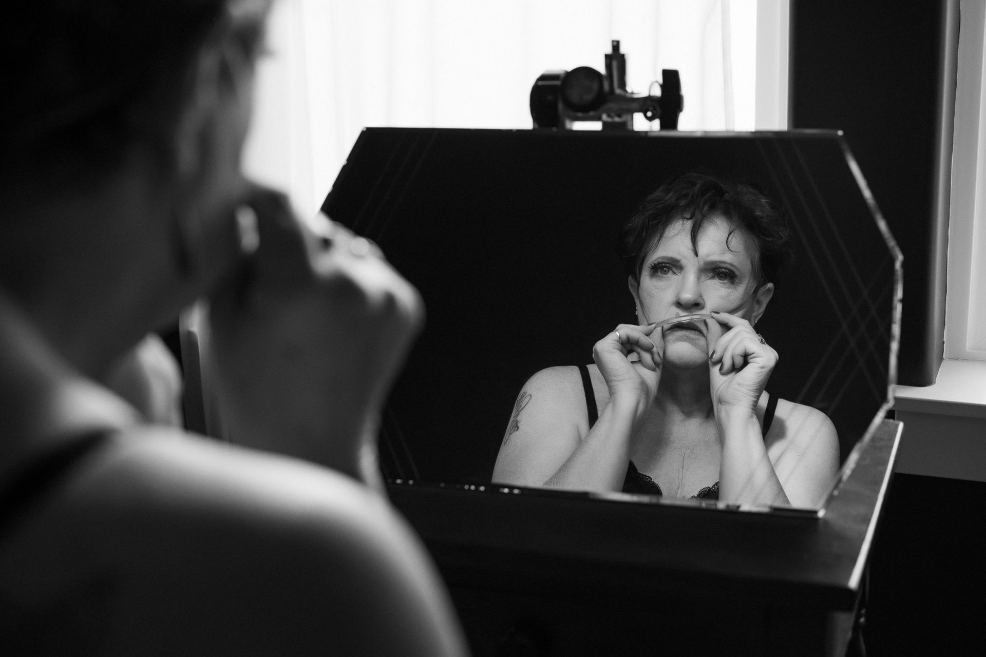 woman looking at her reflection with an oxygen tank