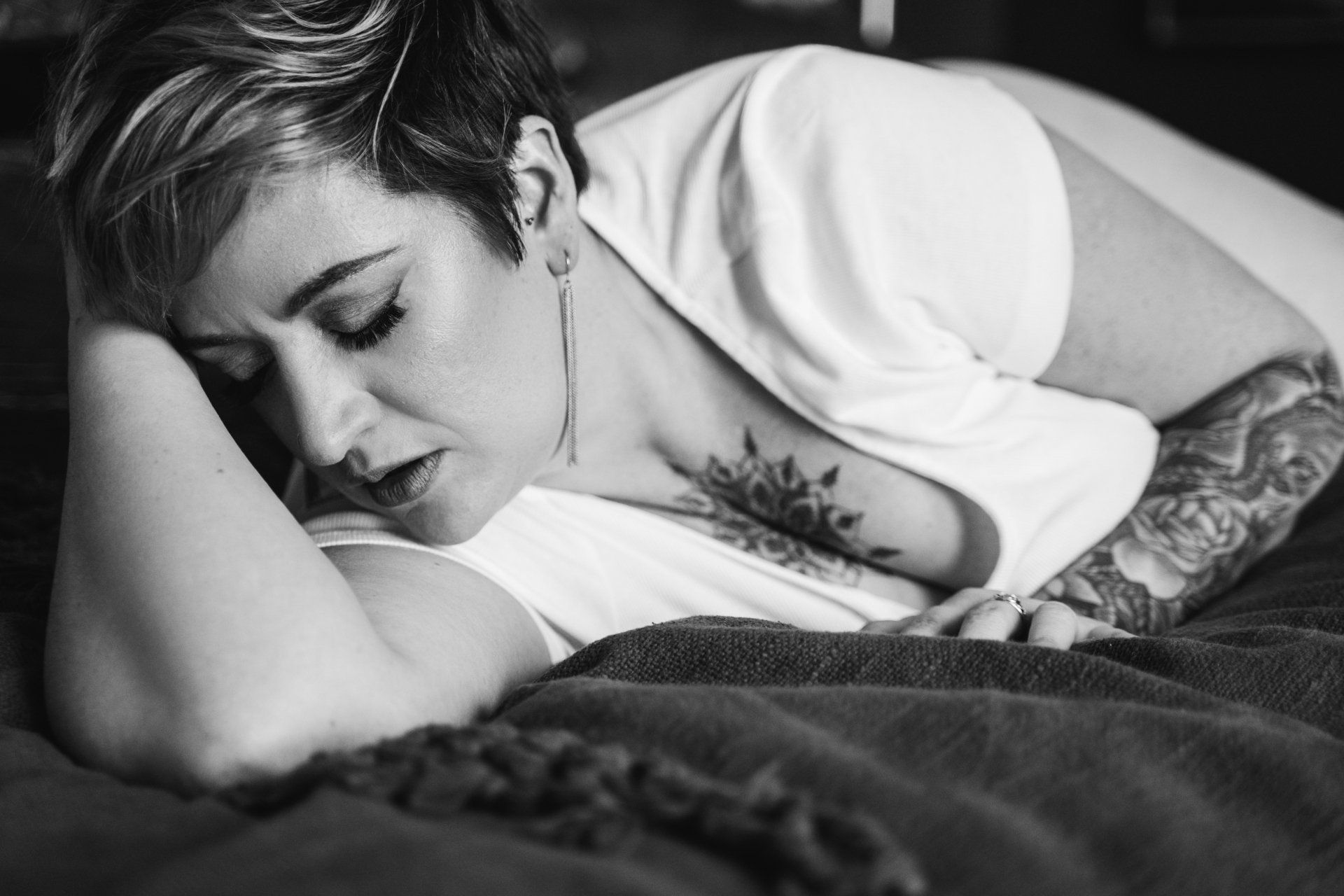 boudoir portrait of a woman lying on her side on a bed with her eyes closed