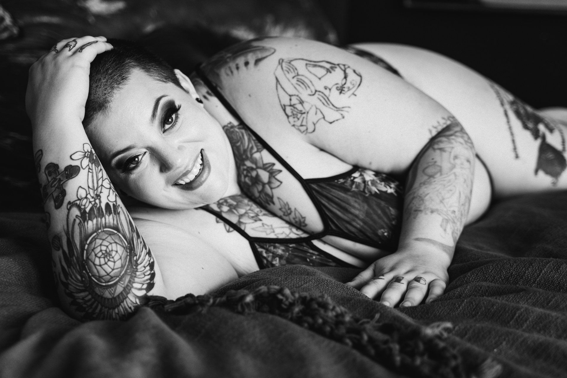 boudoir image of a woman lying on a bed smiling