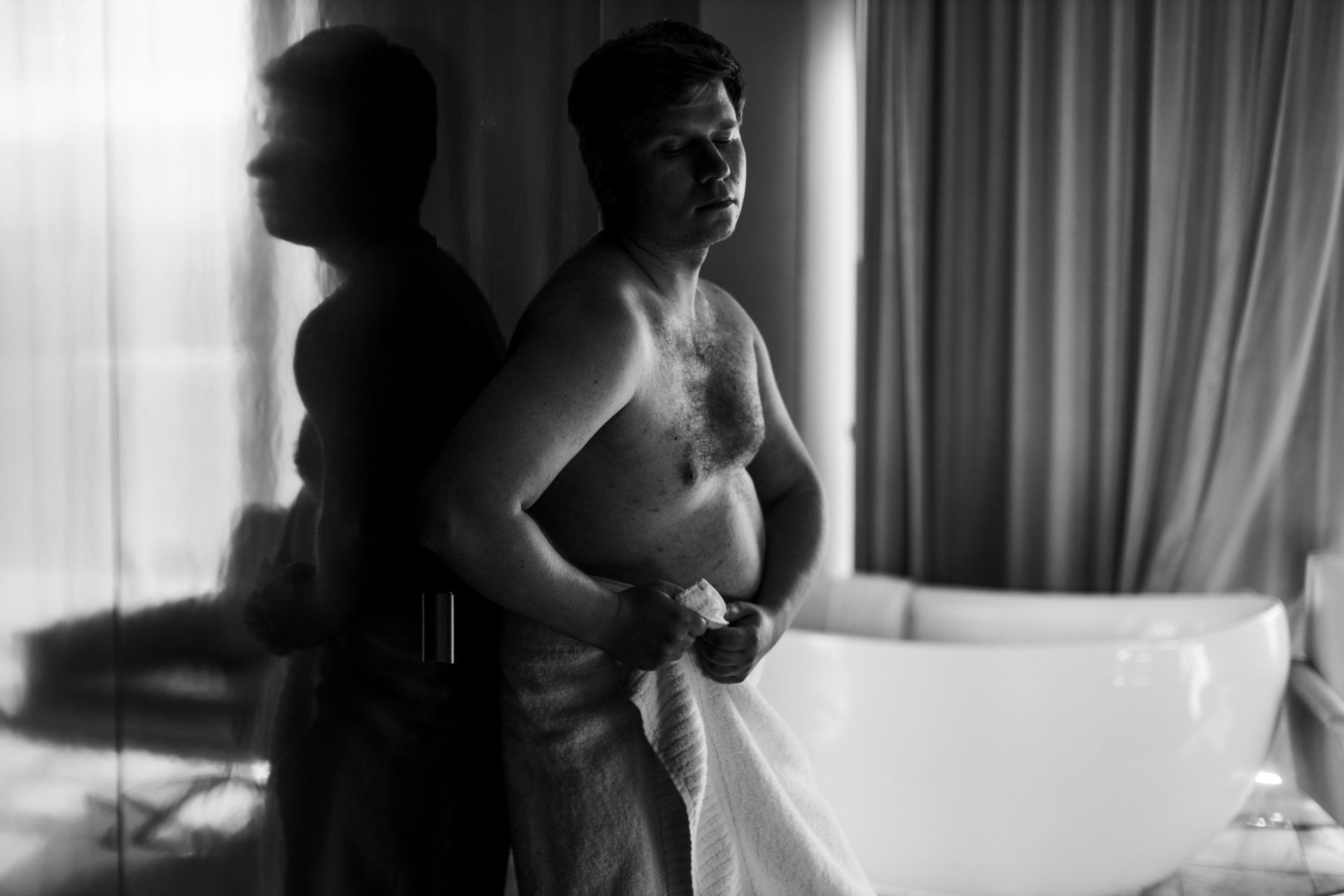 boudoir by Marco Ibanez man standing next to a bathtub wrapped in a towel during his boudoir session