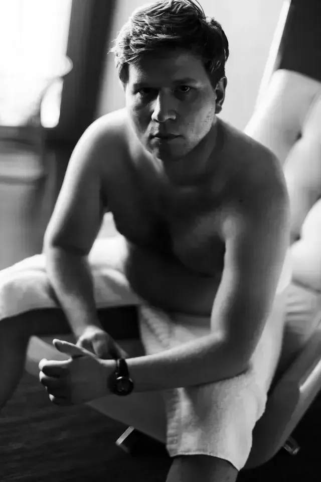 boudoir by Marco Ibanez male sitting down with a towel wrapped around him fixing his watch during the boudoir session