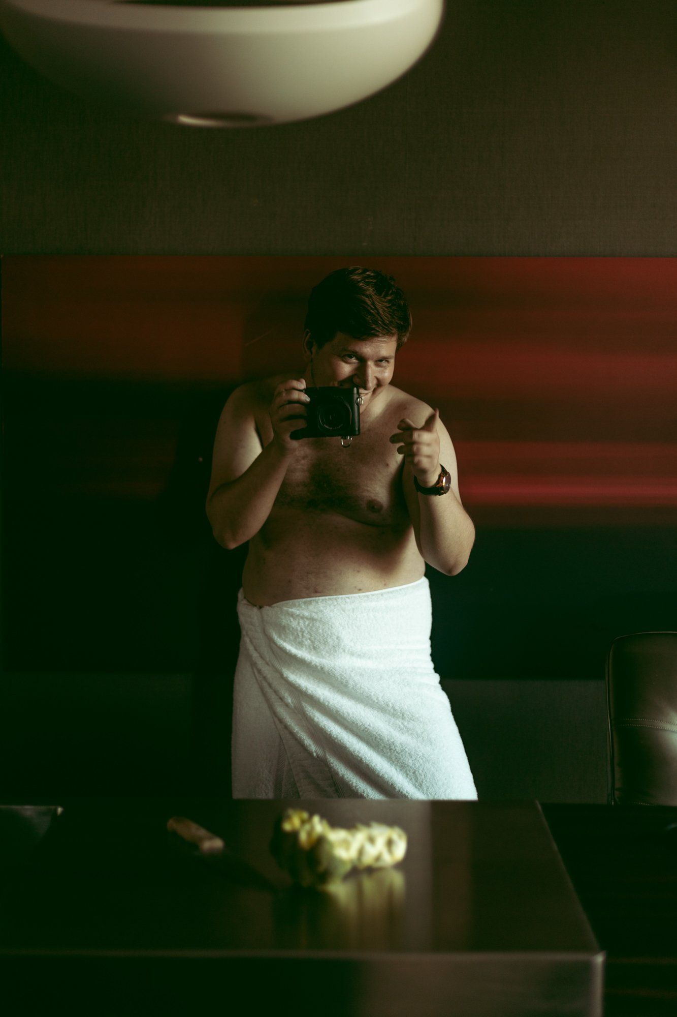 boudoir by Marco Ibanez man standing and laughing wrapped in a towel while holding a camera during his boudoir photo session