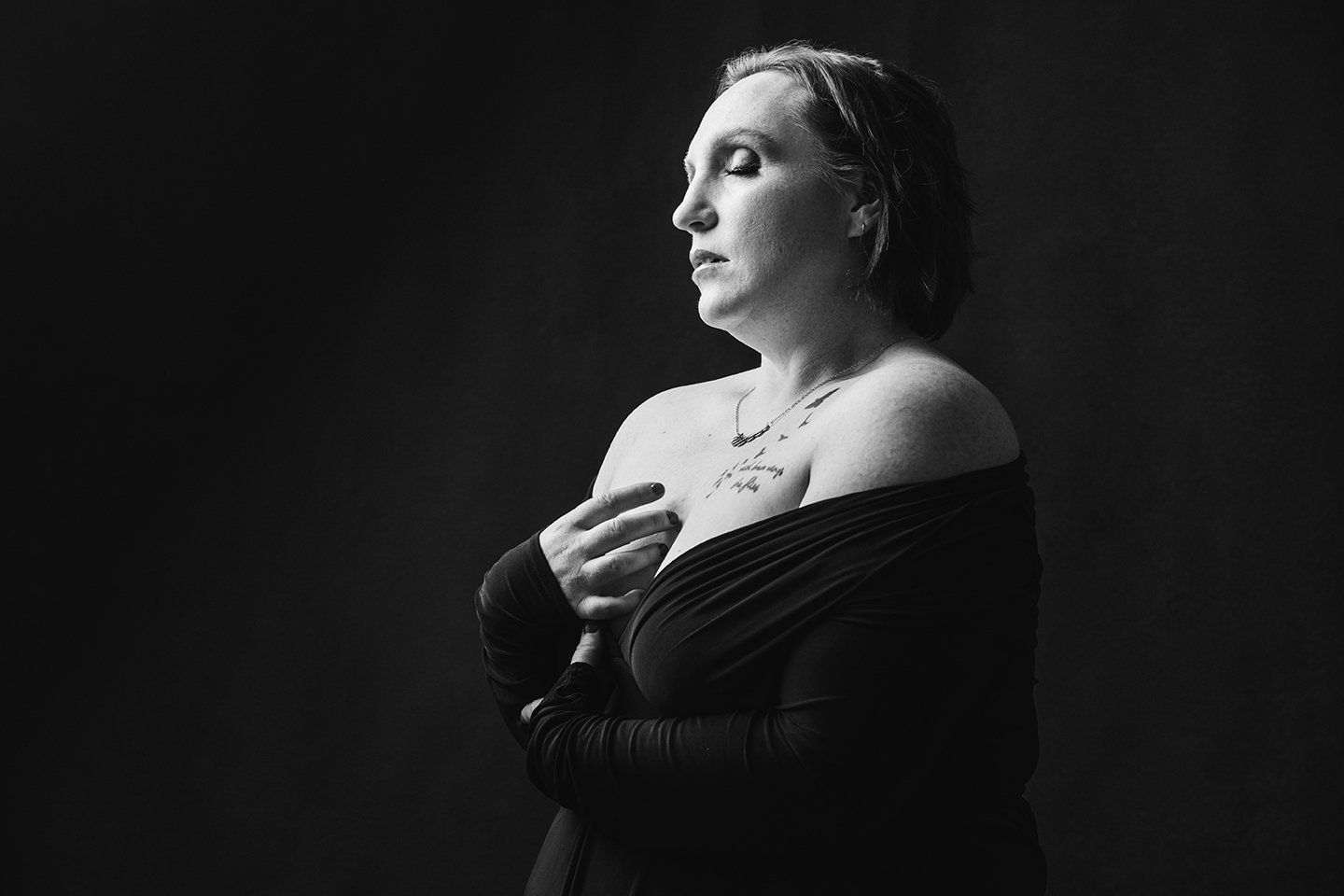 woman in a black dress with eyes closed during her boudoir session in Ogden Utah
