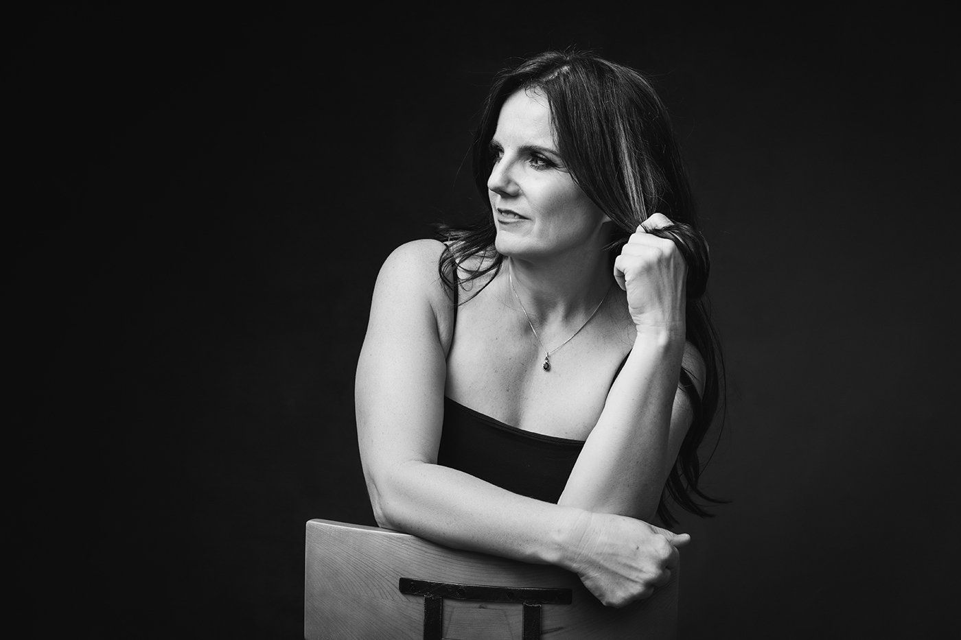 Boudoir Portrait of a woman looking over one shoulder and holding her hair