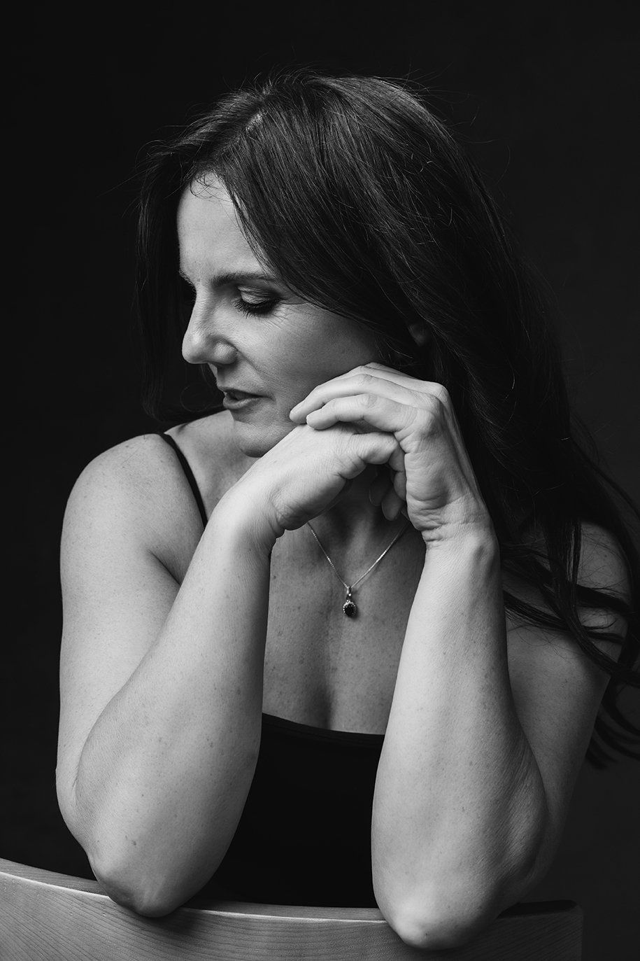 black and white portrait of woman with head to one side and hands clasped