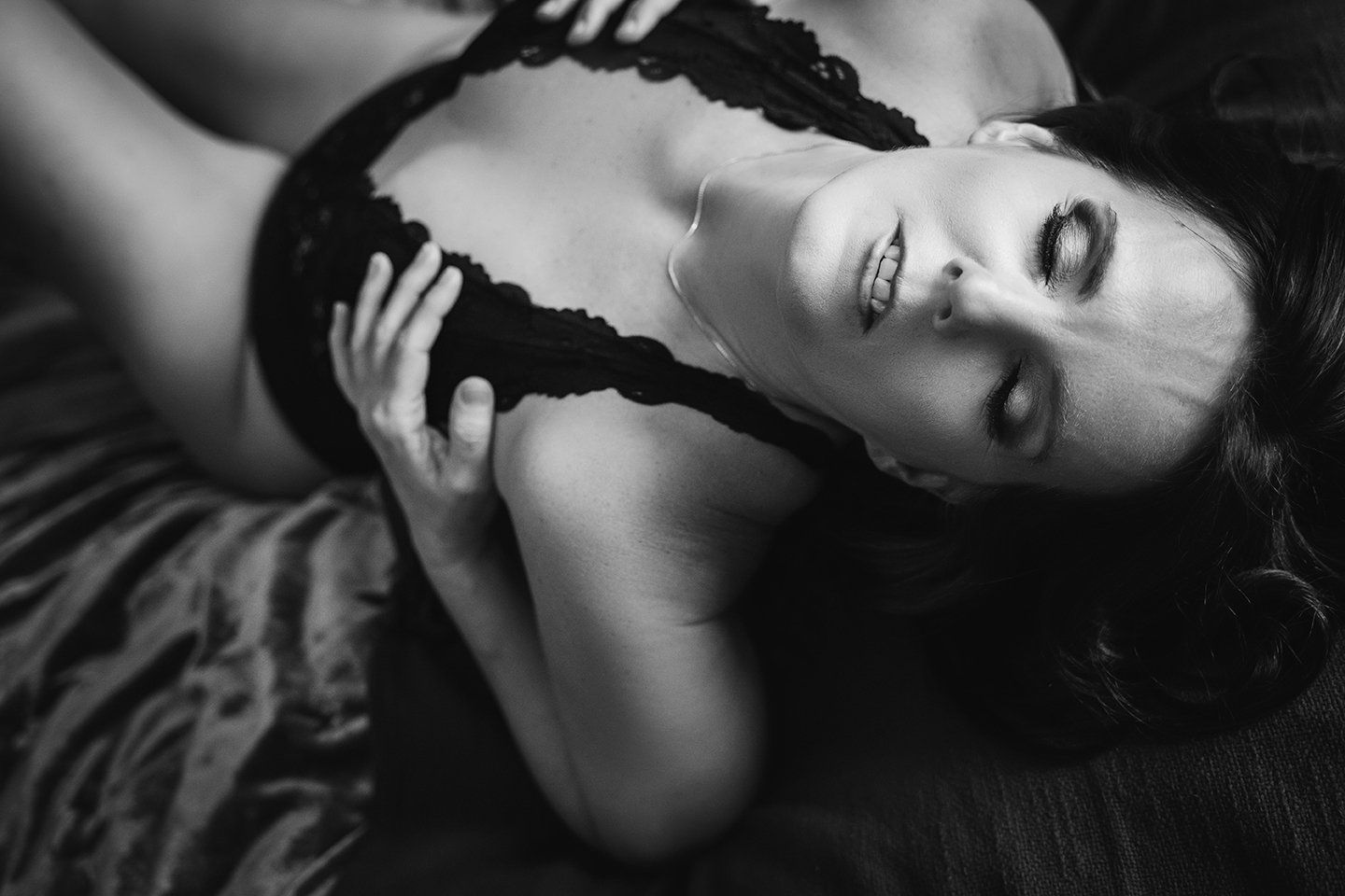 sexy photo of woman on bed, arching with hands on breasts