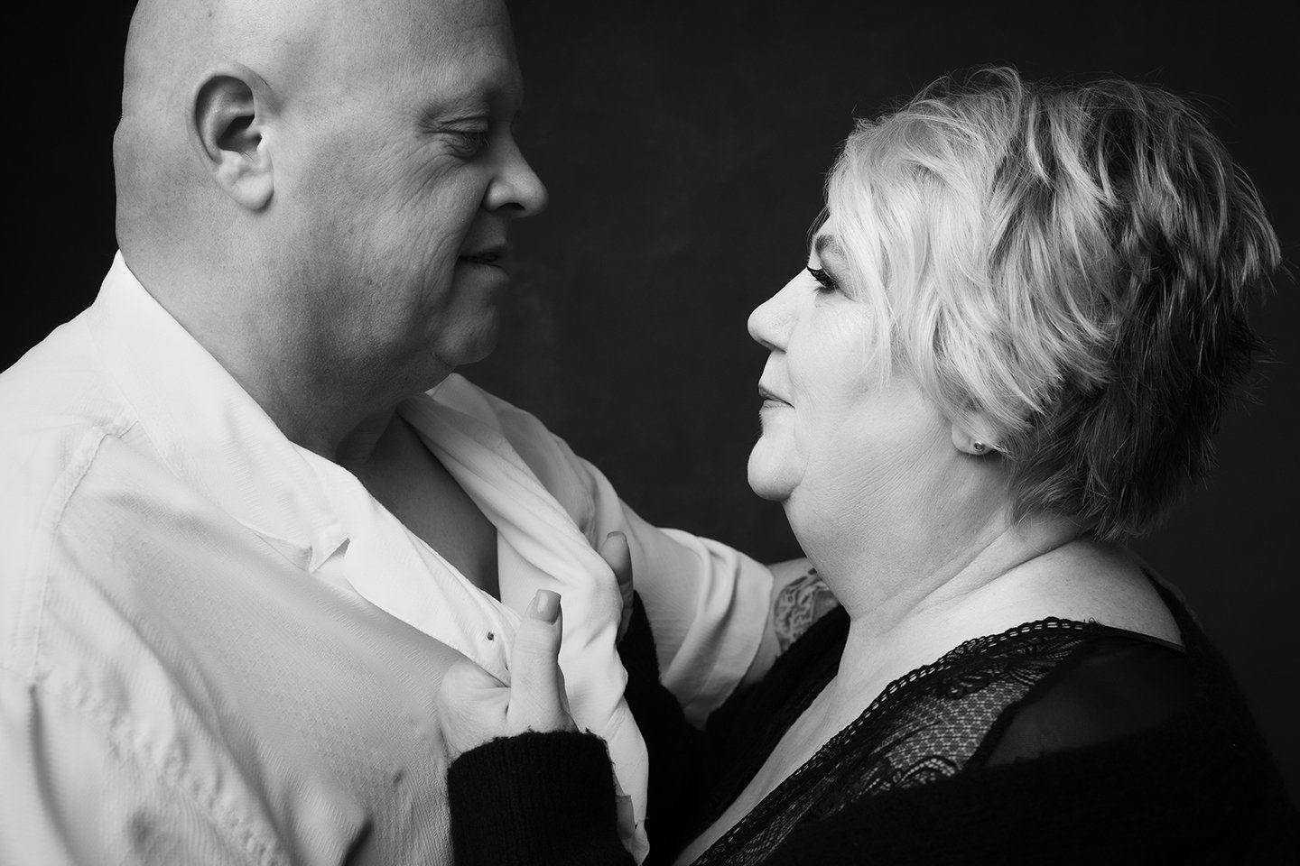 woman holding man's collar, couple looking into each other's eyes