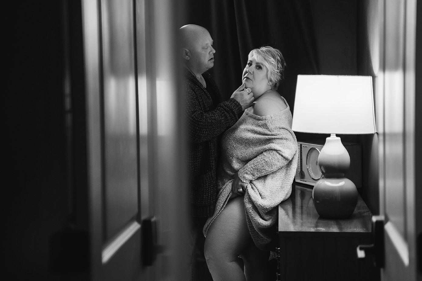 sexy couples shoot, man holding woman's chin, woman looking at camera pulling sweater up