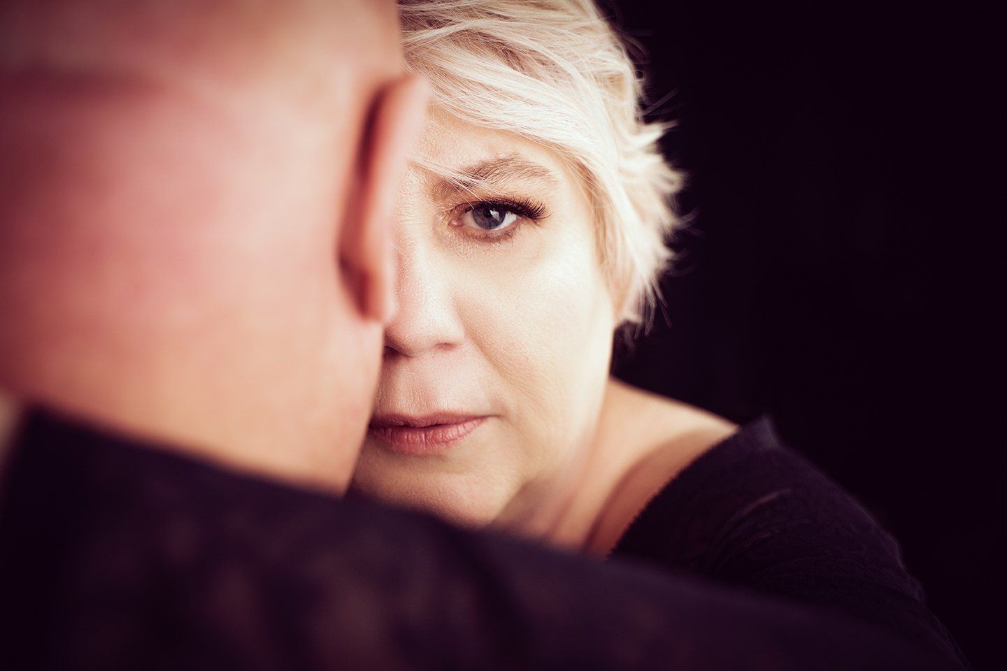 couples portrait, half of woman's face obscured by man, woman looking into camera