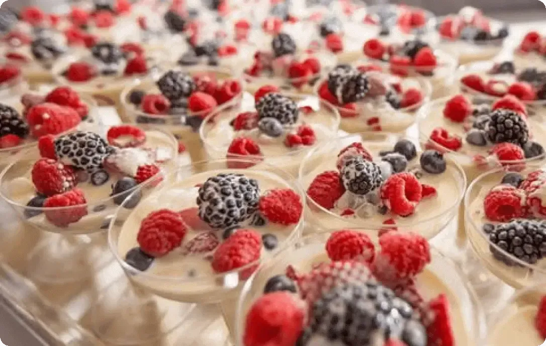 Rows of berry-topped dessert cups with whipped cream in a close-up display