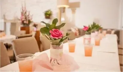 Elegant banquet table with pink floral centerpieces and peach candles in a softly lit event room