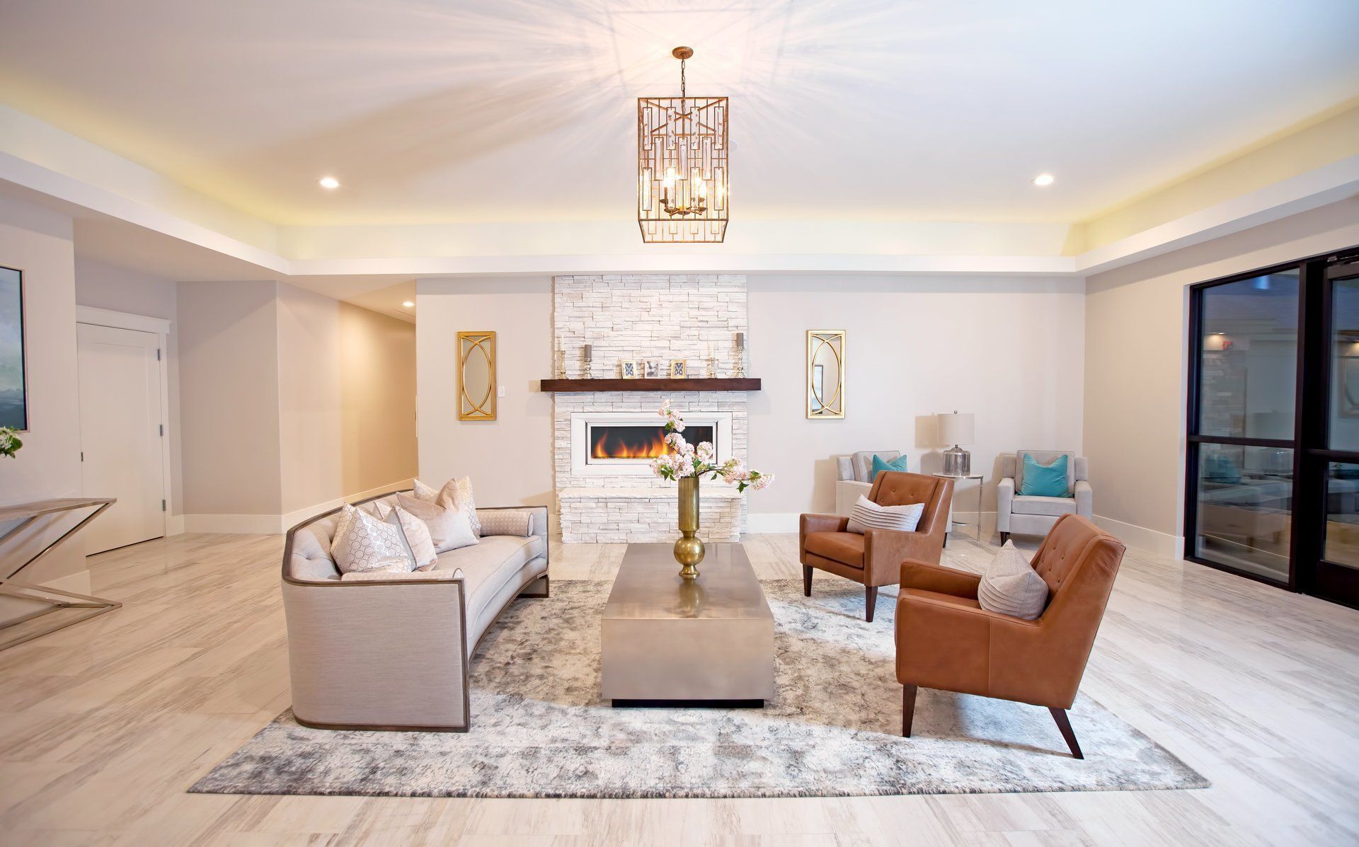 Bright living room with beige sofas, brown chairs, a fireplace, and large windows.