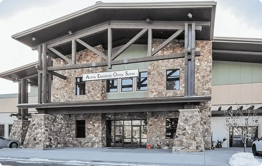 Snow-covered stone lodge-style building with large wooden beams and balconies outdoors