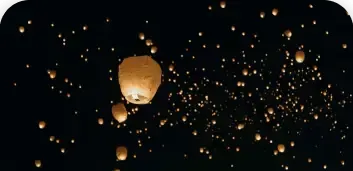 Hundreds of glowing sky lanterns floating in a dark night sky