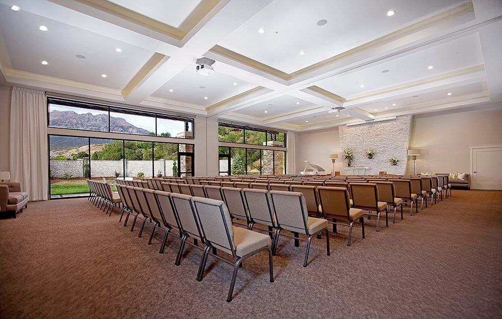 Spacious conference room with rows of chairs, long tables, and large windows letting in natural light