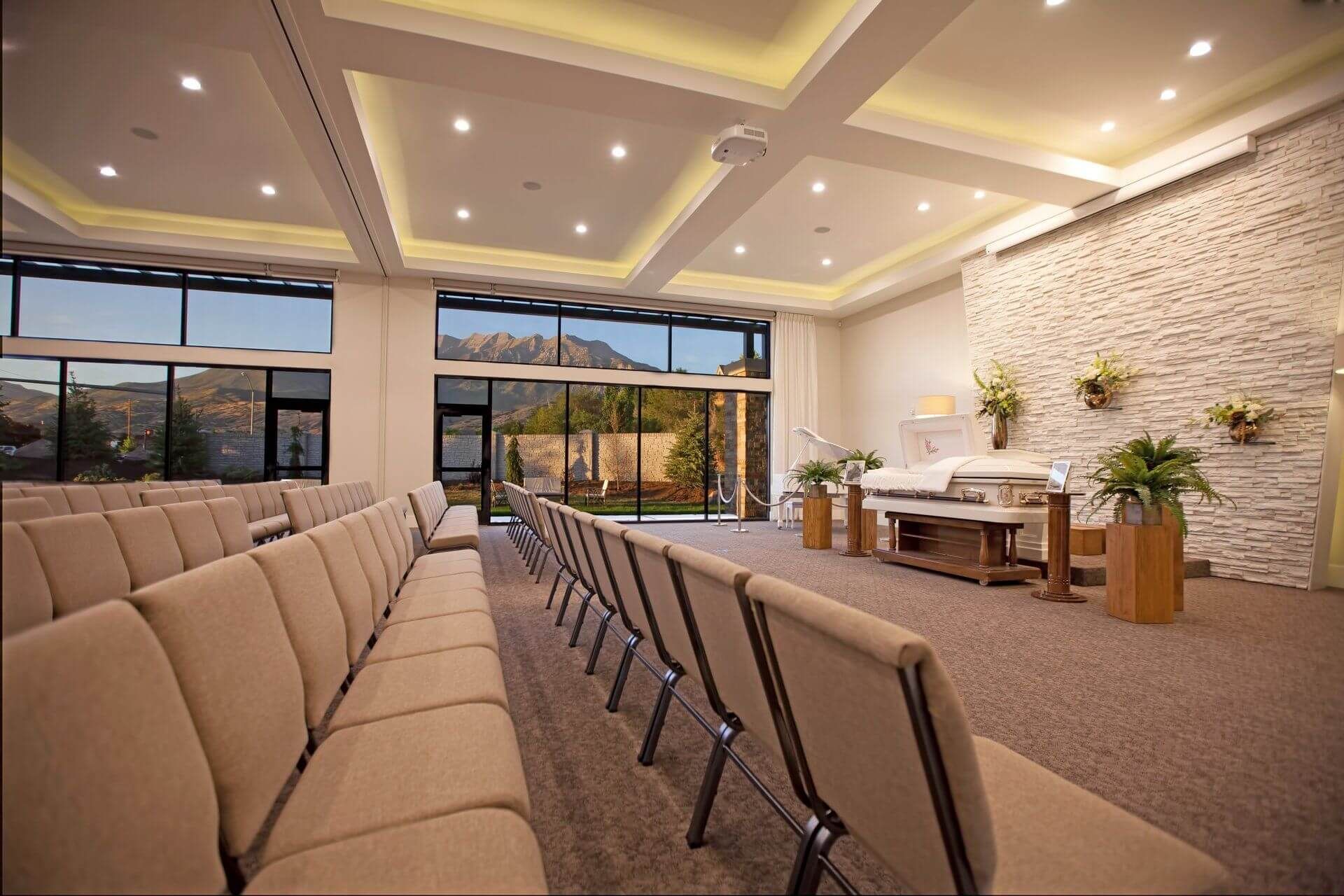 Modern conference room with tan chairs, recessed ceiling lights, and large windows overlooking mountains