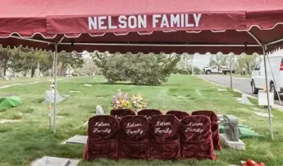 Maroon memorial canopy with “NELSON FAMILY” and four matching chairs on a grassy outdoor field.