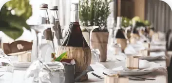 Elegant dining table set with wine bottles, glasses, and candles in a bright restaurant
