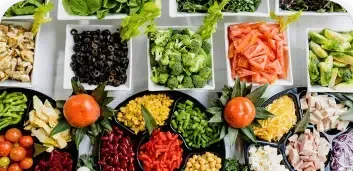 Assorted chopped vegetables and berries arranged in colorful bowls on a market-style display.