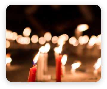 Blurred red candles with warm flames glowing in a dark, out-of-focus setting