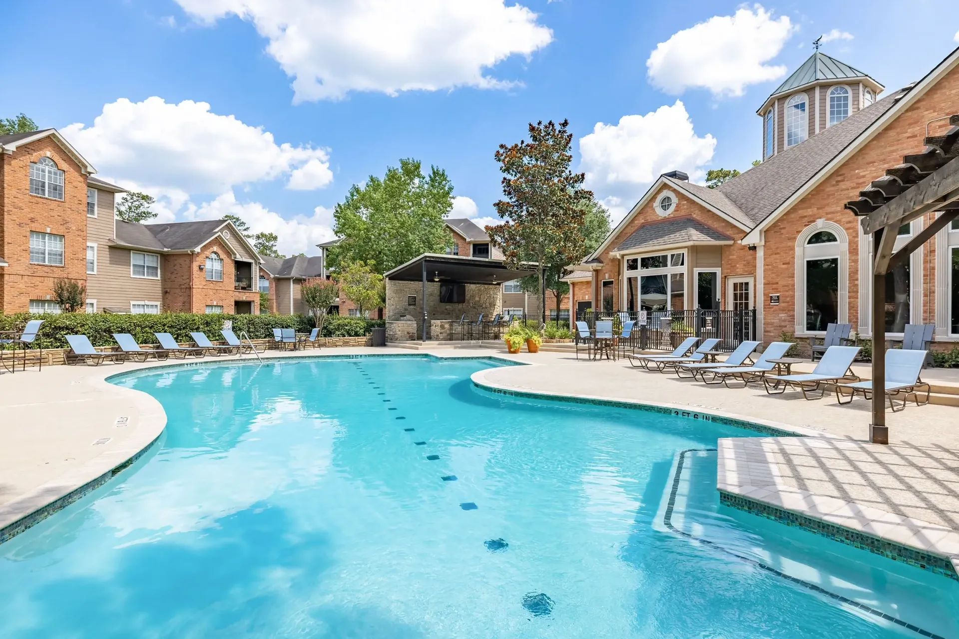 Resort-style swimming pool with lounge chairs and an outdoor kitchen area at a multifamily property.