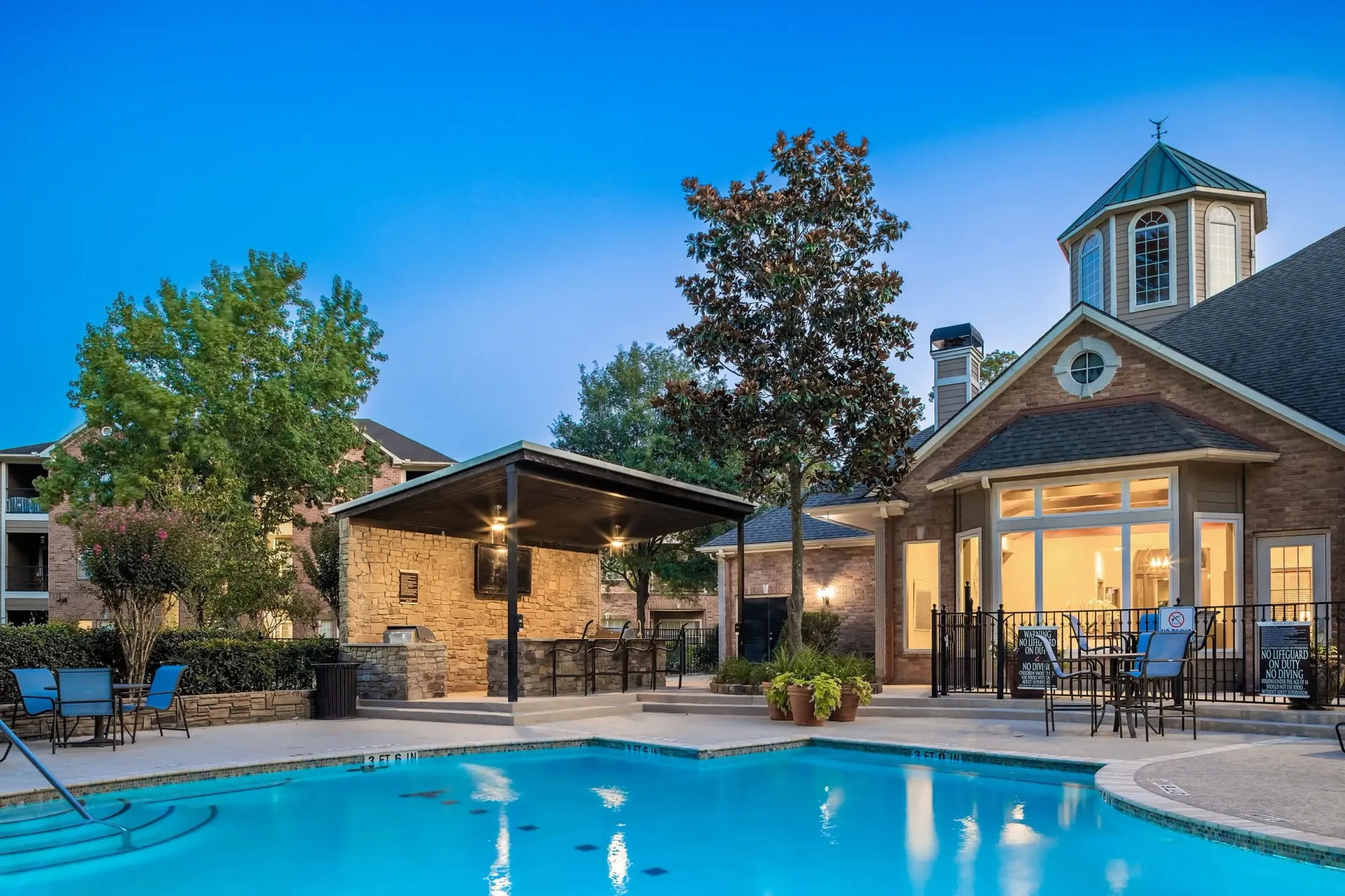 Outdoor swimming pool and covered grilling area at dusk.