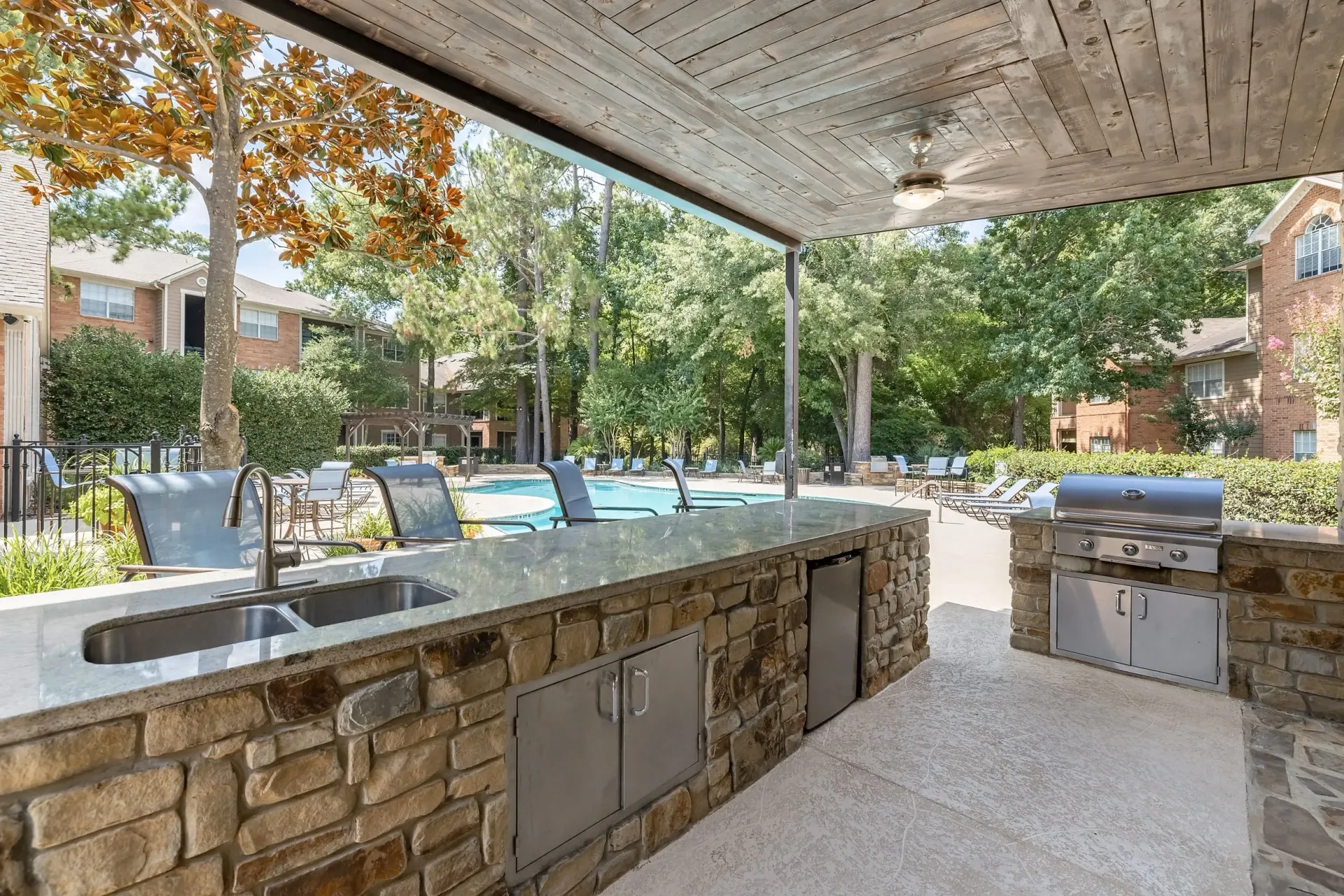 Outdoor kitchen with grill and sink overlooking the pool.