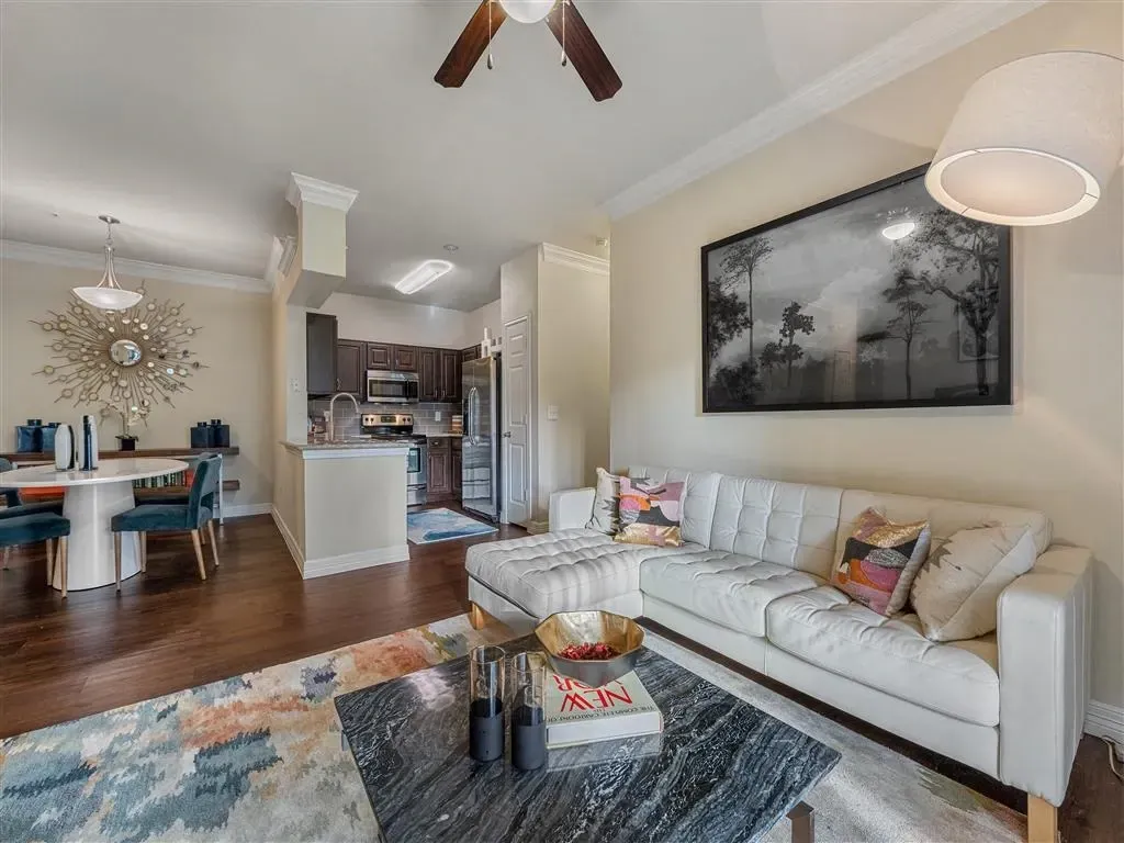 Modern living room with white sofa, coffee table, and view of kitchen and dining area.