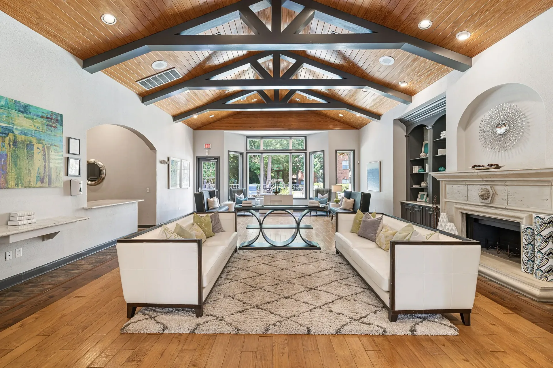 Clubhouse lounge area with sofas, a fireplace, and large windows overlooking the outdoors.