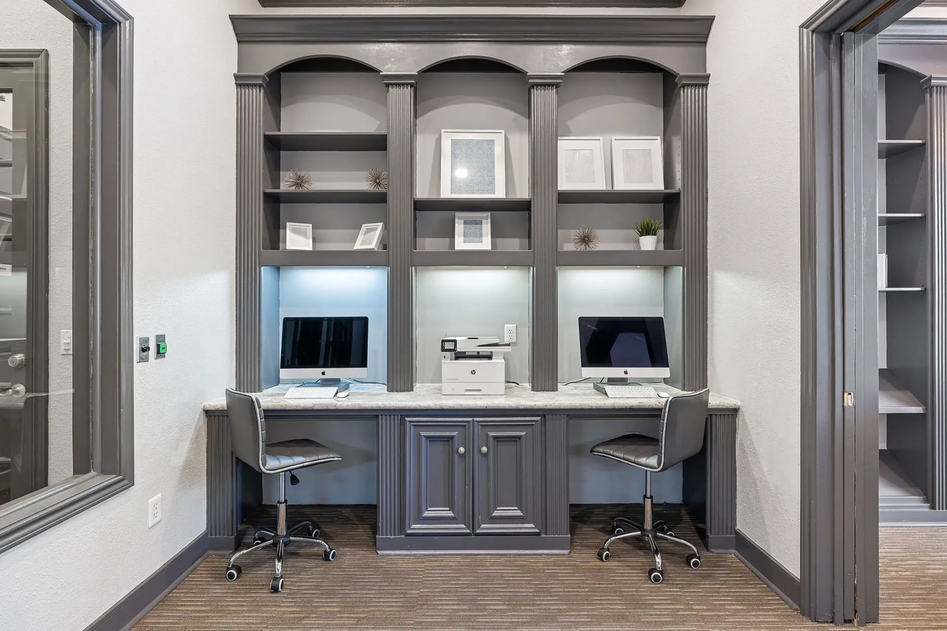 Business center with two Apple computers, a printer, and built-in shelving.