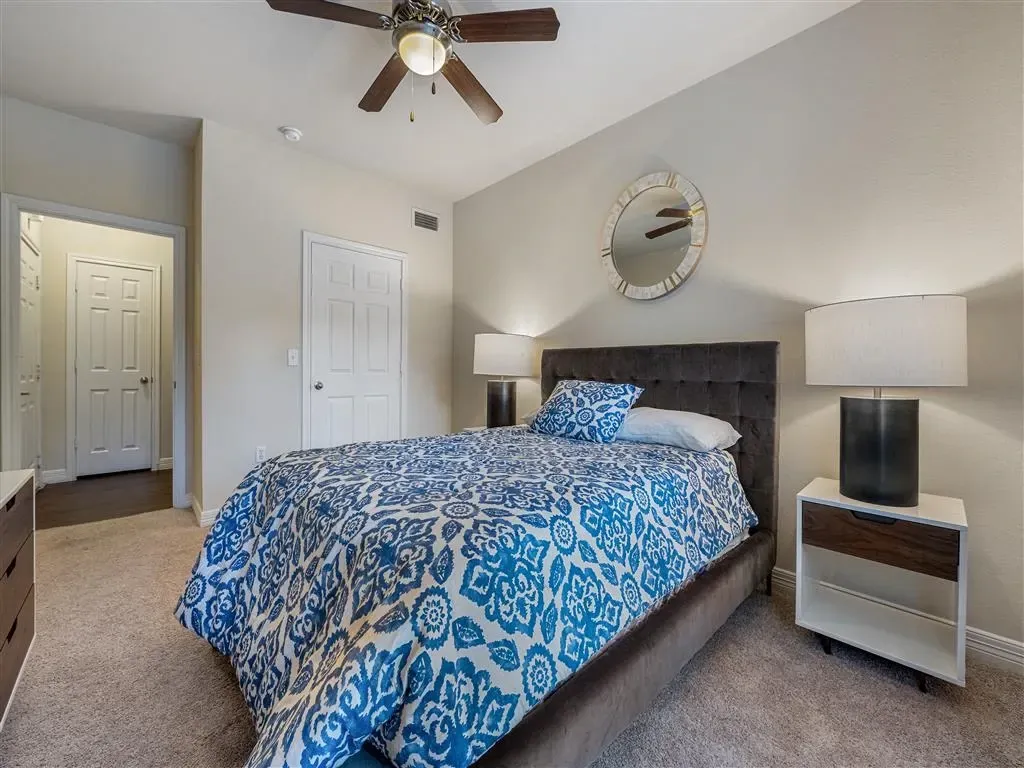 A bedroom with a queen-size bed, bedside table, and closet.