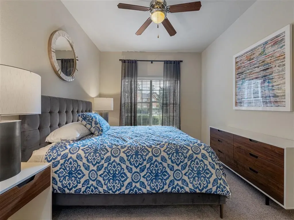 Bedroom with a king-size bed, blue and white patterned comforter, and a dresser.