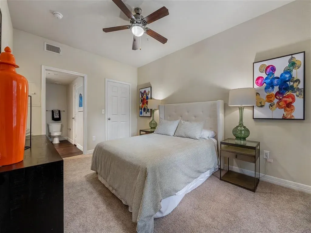 Bedroom with a queen-size bed, nightstand, dresser, and attached bathroom.
