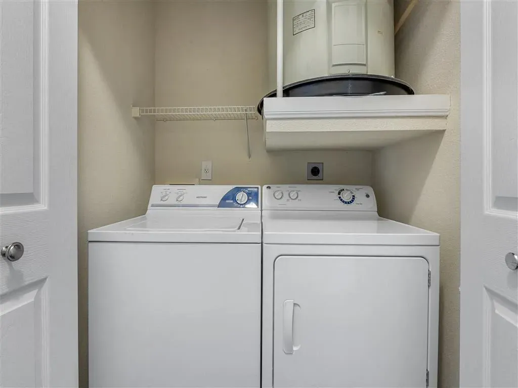 Full size washer and dryer with storage shelf and water heater.