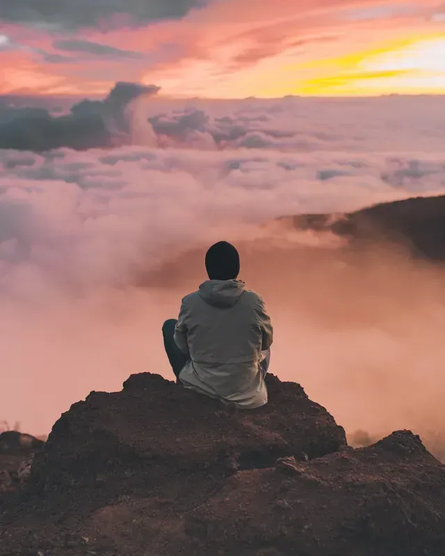 A Man Is Sitting on Top of A Mountain Looking at The Clouds — Moving Beyond OK In Mount Warren Park, QLD